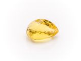 a close up of a yellow sapphire stone on a white surface