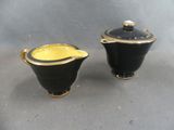 pair of black and gold sugar and creamers