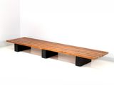 a wooden bench with two black legs in a white room