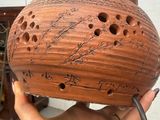 a person holding a brown vase with writing on it