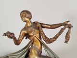 bronze statue of a woman holding a bird on a pedestal