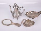 a silver tea pot, spoon, and other items on a white surface