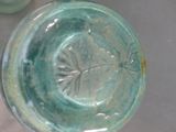 a green glass vase with a flower inside of it