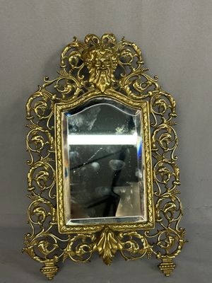 a mirror hanging on the wall with a gold frame