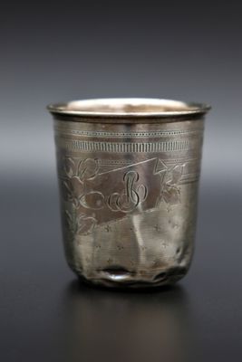 une vieille coupe en argent posée sur une table, sur laquelle figure un monogramme