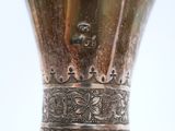 a silver vase that has a metal handle on it