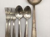 four spoons and a fork are sitting on a white surface
