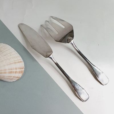 two forks and a knife on a table next to a shell