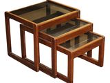 three wooden nesting tables with glass tops on a white background