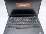 the laptop is open on a white surface with a red lenovo logo on the screen