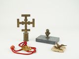 une petite statue représentant un oiseau et une croix, à côté d'une autre petite statue représentant un oiseau et une croix