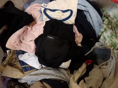un tas de vêtements sur un lit, à côté d'un sac
