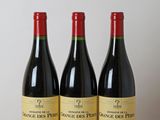 trois bouteilles de vin rouge sont posées sur une table en bois