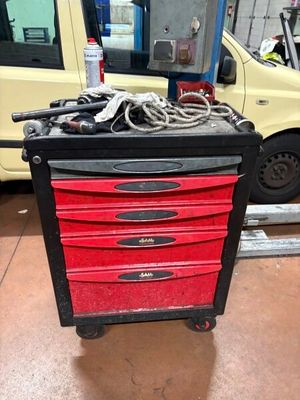 une boîte à outils rouge sur laquelle sont posés des outils, dans un garage