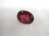 a close up of a red ruby stone on a white surface