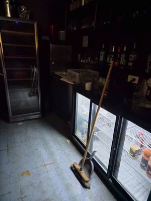 une serpillière et un balai devant un réfrigérateur