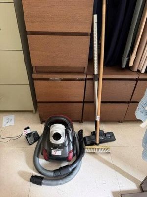 un aspirateur posé par terre à côté d'un balai