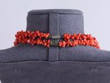 a close up of a necklace with coral beads on a mannequin