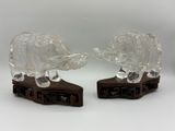 une paire d'éléphants en verre transparent posés sur des socles en bois, sur fond blanc