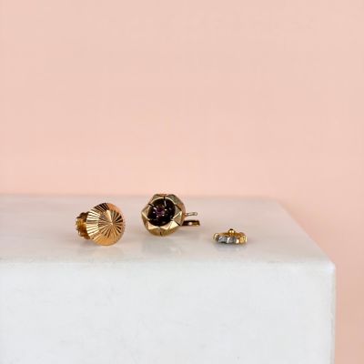 two pairs of gold and garnetite stud earrings on a marble block