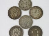 six different british coins sitting on top of each other on a white surface