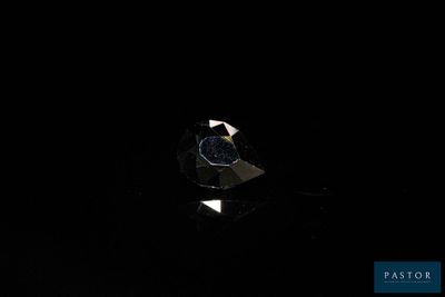 un gros plan d'un diamant posé sur une surface noire dans l'obscurité