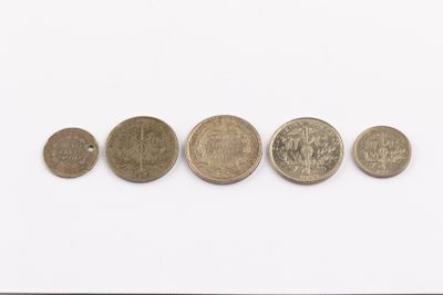 five different coins are arranged in a row on a white surface
