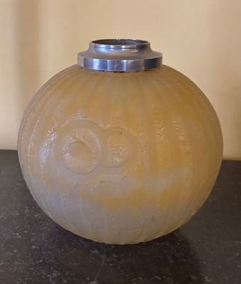 un vase en verre muni d'un couvercle en argent, posé sur une table