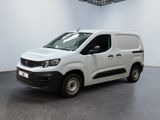 La camionnette blanche est garée dans une grande pièce au sol noir.