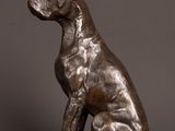 a bronze statue of a dog sitting on top of a wooden table