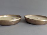 two gold bowls with a candle in them sitting on a table