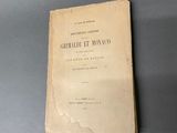 un vieux livre posé sur une table à côté d'un mur gris