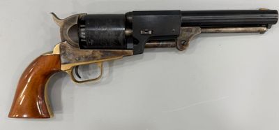 un vieux revolver avec une poignée en bois sur une surface blanche
