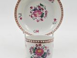 a white plate with pink flowers on it and a saucer on a stand