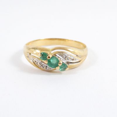 a close up of a gold ring with a green stone and diamonds