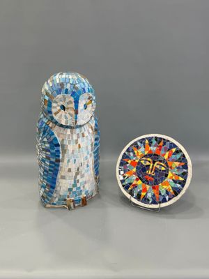 un petit hibou posé à côté d'une petite horloge sur une table