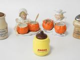 several figurines of children and a jar of milk on a white surface