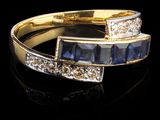 une photo d'une bague sertie d'un diamant et d'un saphir sur un fond noir