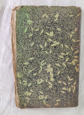 un vieux livre posé sur une table recouverte d'un tissu blanc