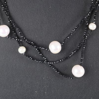 a close up of a black and white necklace with pearls