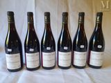 six bottles of wine are lined up in a row on a table