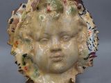 une sculpture en céramique représentant le visage d'une femme, posée sur un socle