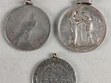 three silver coins and a silver coin on a white surface