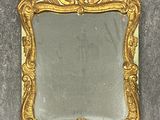 un miroir au cadre doré ouvragé posé sur une surface grise