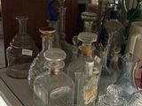 many glass bottles and a plate on the counter
