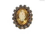 une photo d'une bague ornée d'une grosse pierre jaune entourée de petits diamants blancs