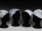 trois têtes de mannequins coiffées de chapeaux blancs sur fond noir