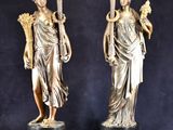 une paire de statues antiques en bronze représentant des femmes tenant des torches