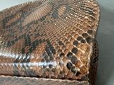 a brown and black snake skin purse sitting on a table