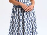 La femme porte une robe bleue et blanche à motifs circulaires.